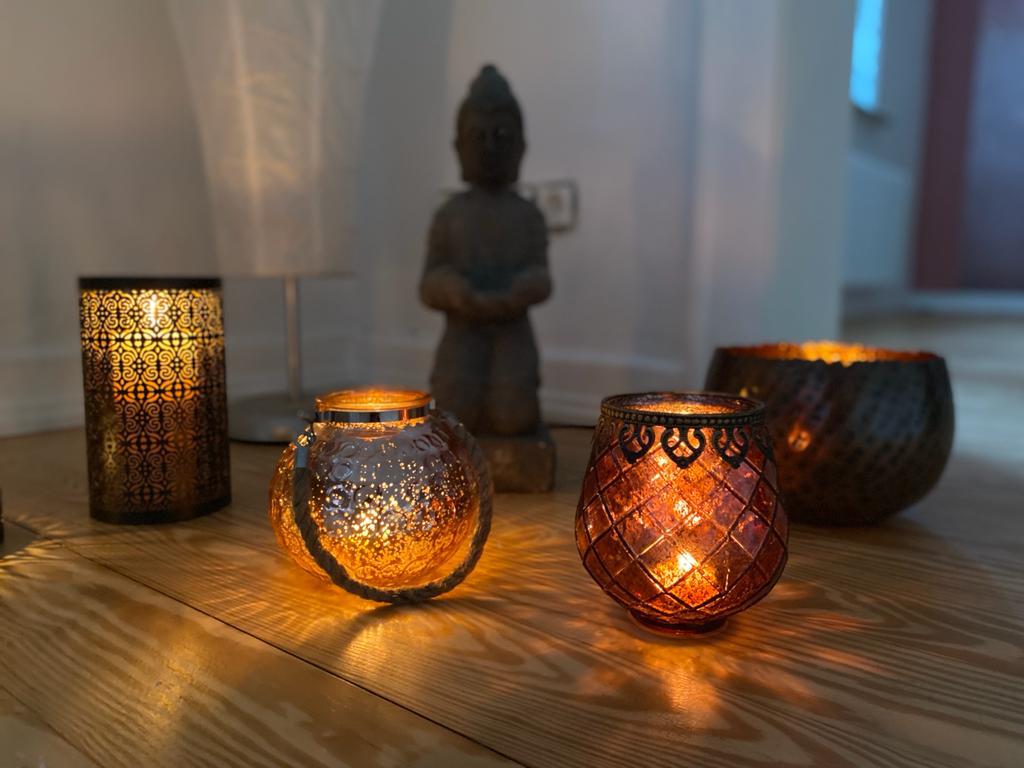 Teelichter vor Buddhafigur Teelichter auf Holzfussboden und Buddhafigur
